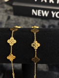Gold-toned bracelets with detailed clover-shaped motifs on a black velvet display