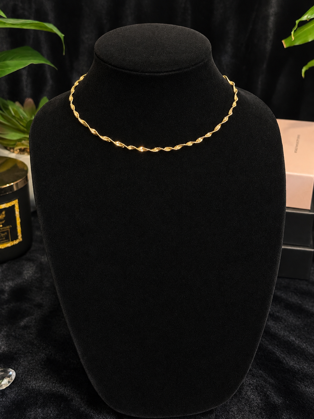 Gold-toned twist chain necklace displayed on a black velvet bust