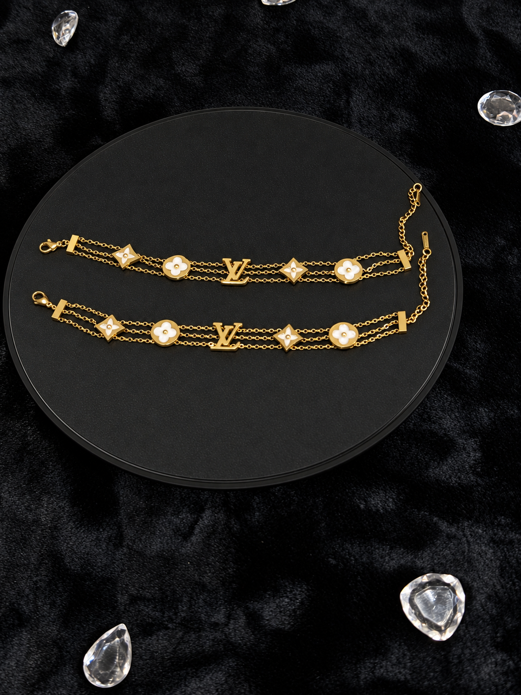 Gold-toned triple-chain bracelets with pale floral motifs on a black display