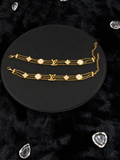 Gold-toned triple-chain bracelets with pale floral motifs on a black display